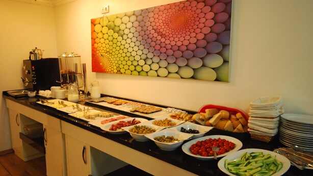 A buffet with various food items and a colorful abstract painting on the wall.