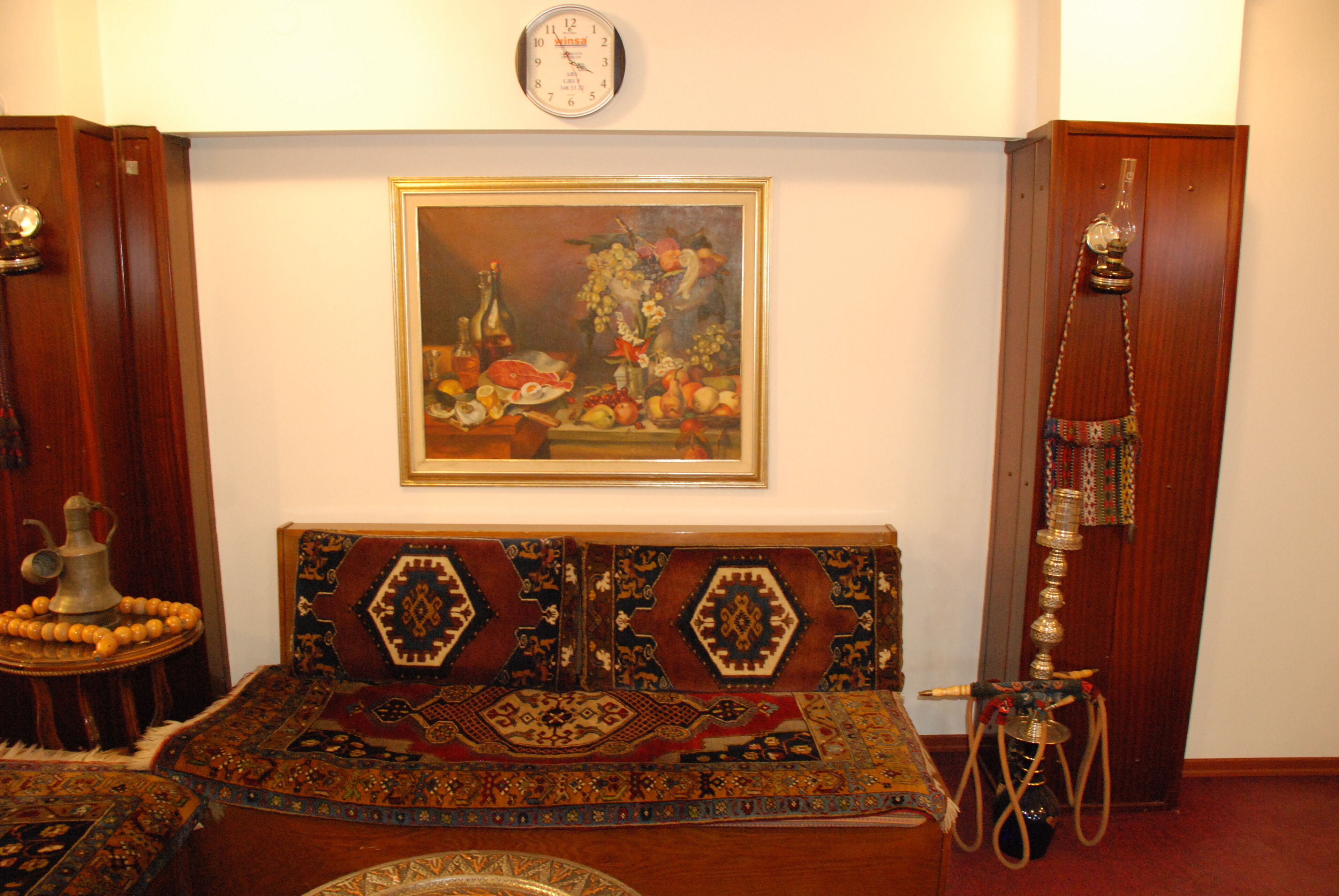 Una habitación tradicional con un sofá estampado, un reloj de pared y un cuadro con frutas y flores.