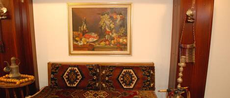 Una habitación tradicional con un sofá estampado, un reloj de pared y un cuadro con frutas y flores.