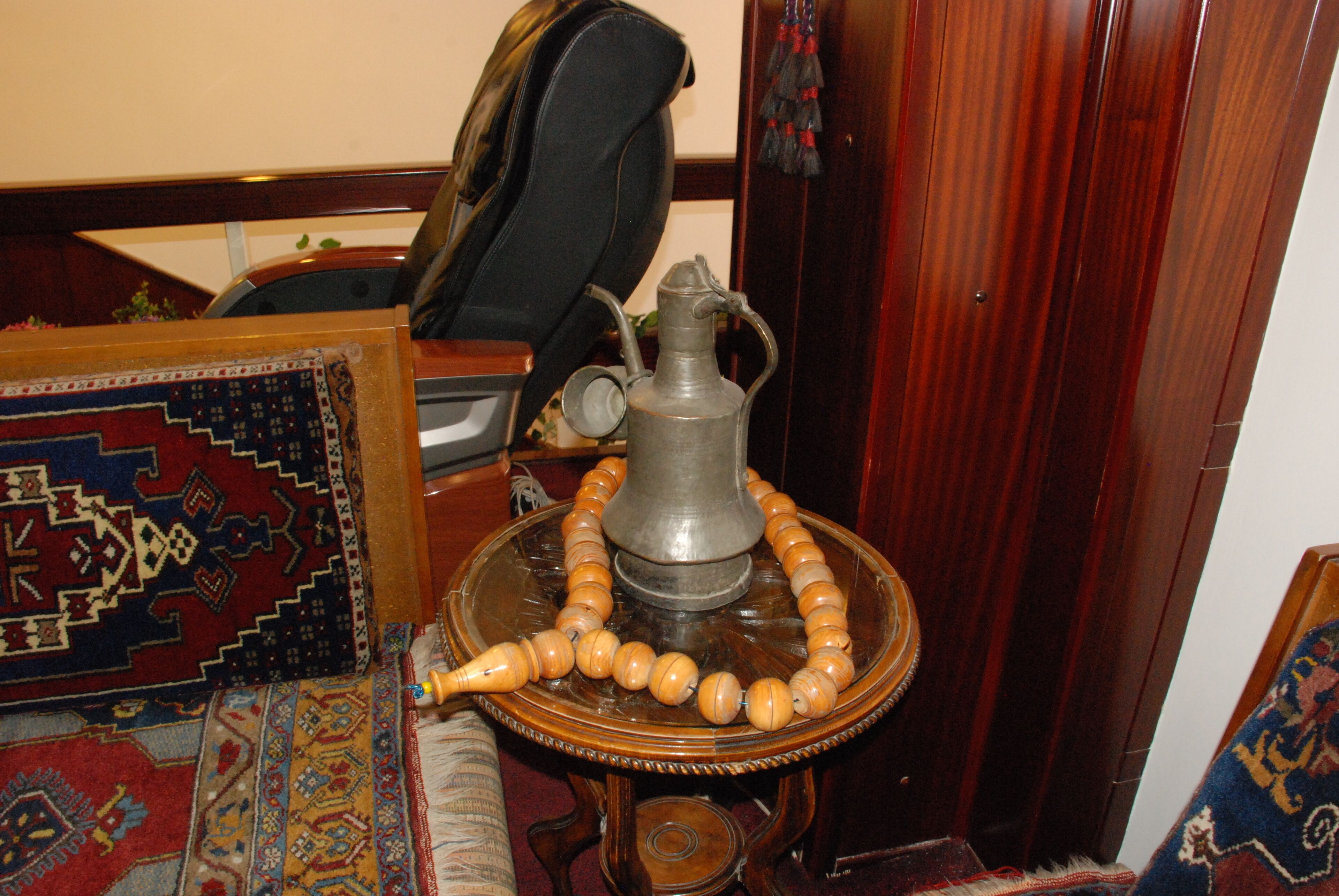 A traditional tea set on a wooden table, a patterned rug, and a dark wooden door.