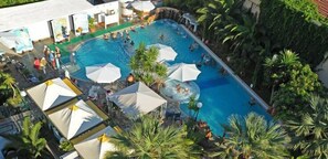 A large outdoor swimming pool surrounded by palm trees and umbrellas, with people swimming and lounging. - Hotel & Spa Kentrikon (Istiaia-Aidipsos)
