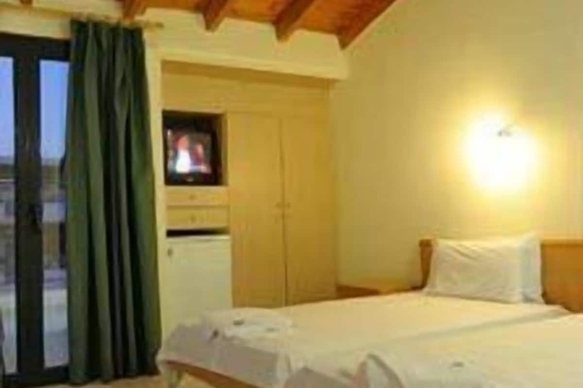 Ein Schlafzimmer mit zwei Betten, einem Fernseher und einer Schiebetür zum Balkon.