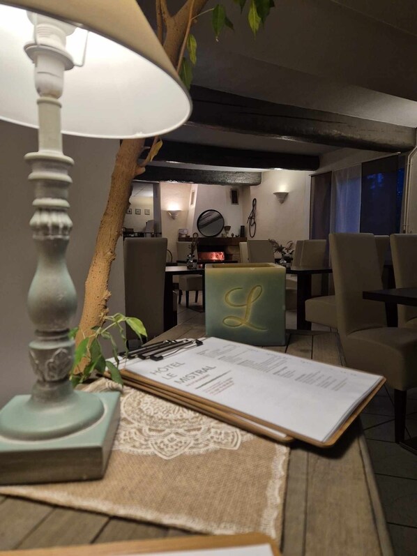 Una habitación de hotel acogedora con una mesa de madera, una lámpara, un cuaderno y un reposapiés verde con un monograma.