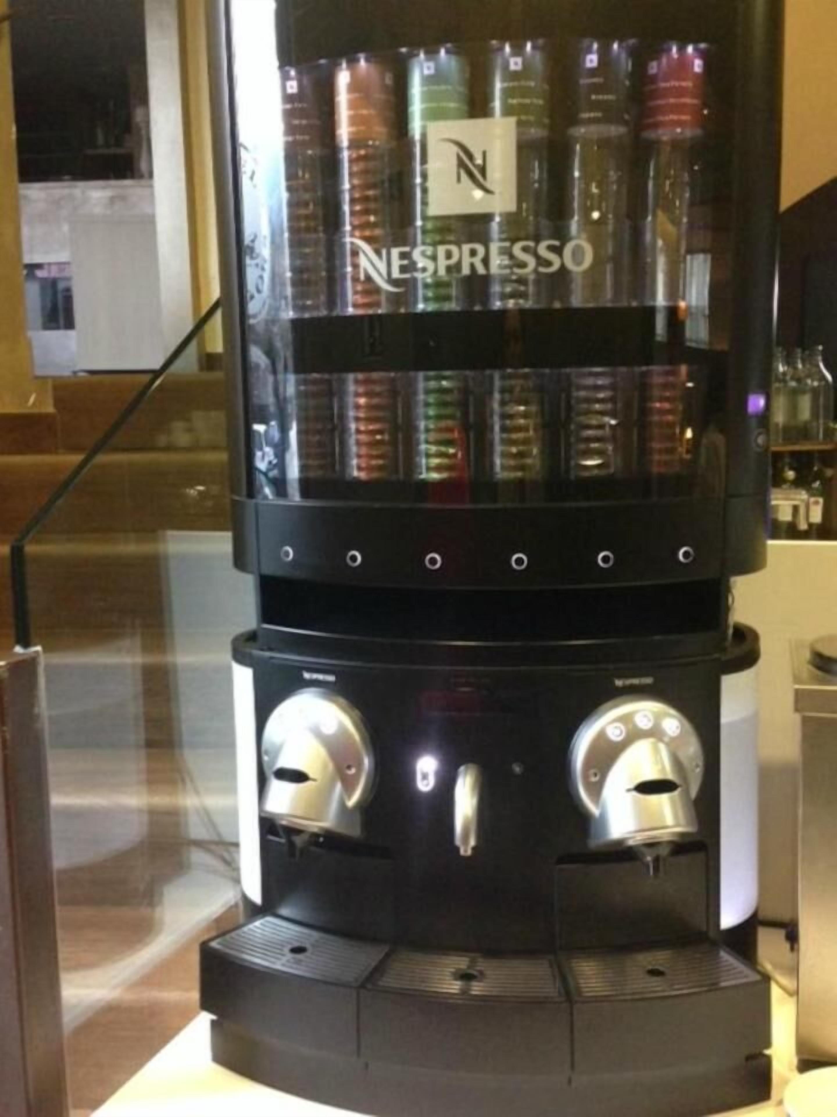 Una máquina de café Nespresso con varios cápsulas de café y dos mandos de control.