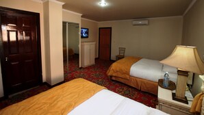 Une chambre d’hôtel avec deux lits, une télévision, un bureau avec une lampe et une chaise.