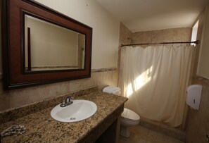 A bathroom with a granite countertop sink, a mirror, a toilet, and a shower curtain.