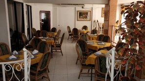 Un espace repas avec des tables disposées pour accueillir quatre personnes, chacune étant recouverte d’une nappe jaune et agrémentée de chaises assorties.