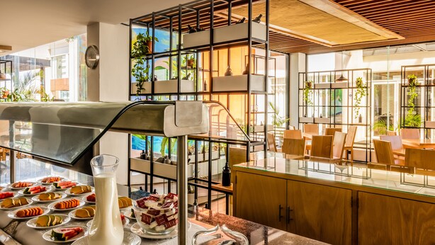 A breakfast buffet with various dishes, a milk pitcher, and a coffee pot. - Wyndham Garden Cancun Downtown (Cancun)