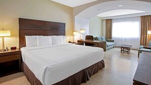 A hotel room with a large bed, a desk, a chair, and a sofa. - Wyndham Garden Cancun Downtown (Cancun)