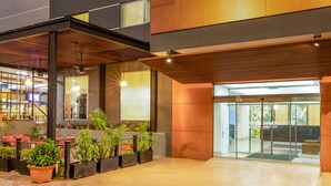 A modern indoor space with a wooden ceiling, potted plants, and a glass door leading outside. - Wyndham Garden Cancun Downtown (Cancun)