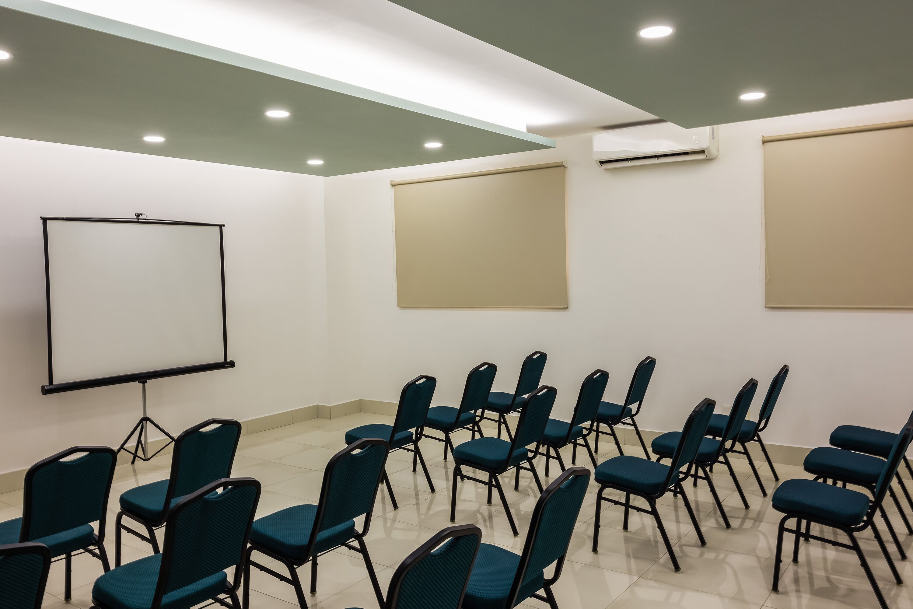 A conference room with a whiteboard, beige walls, and a ceiling with recessed lighting.