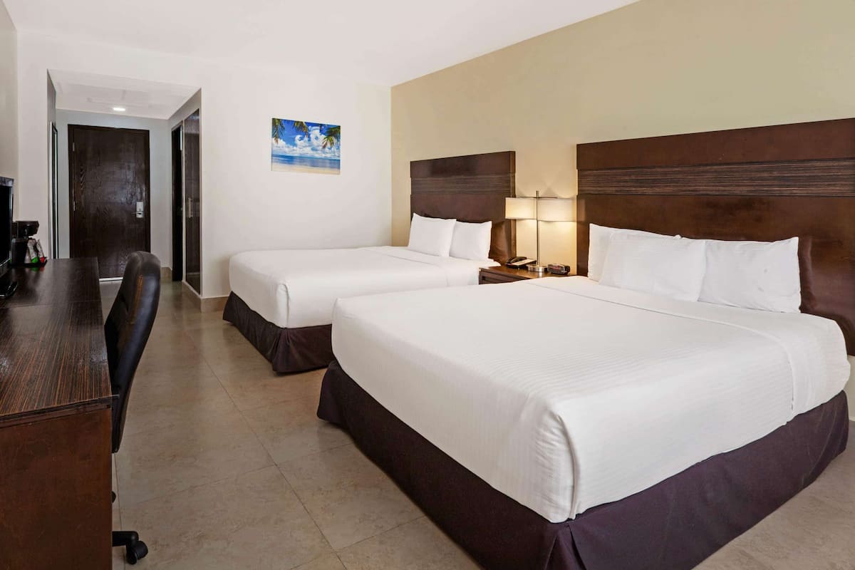 Habitación de hotel con dos camas, un escritorio y una silla.
