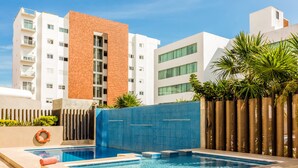 A modern hotel with a swimming pool, a brick facade, and a blue-tiled wall. - Wyndham Garden Cancun Downtown (Cancun)