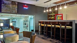 A modern bar area with high stools, a glass partition, and a neon sign. - Wyndham Garden Cancun Downtown (Cancun)