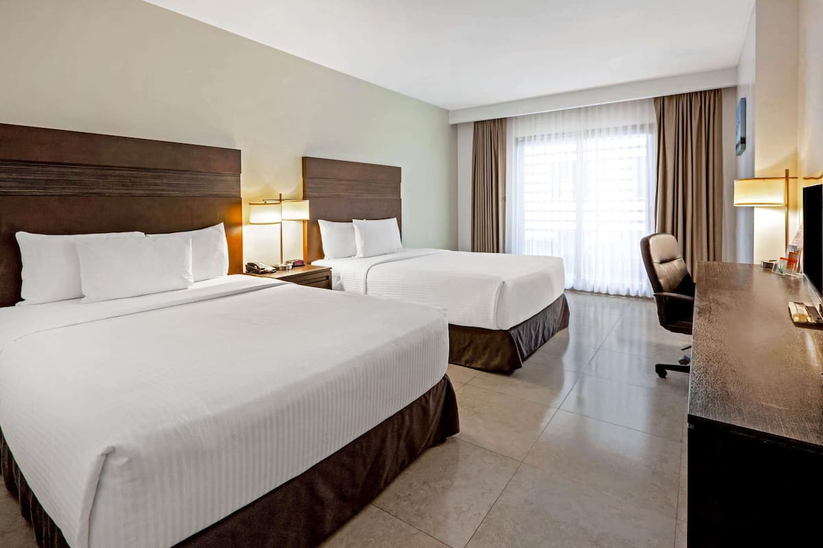 Una habitación de hotel con dos camas, un escritorio, una silla y un televisor.