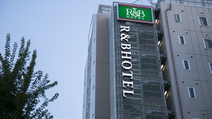 Un edificio alto con un cartel que dice "R&B HOTEL" y un cartel más pequeño encima que también dice "R&B HOTEL".