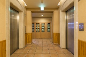 Un couloir avec deux ascenseurs et un espace central doté de placards.