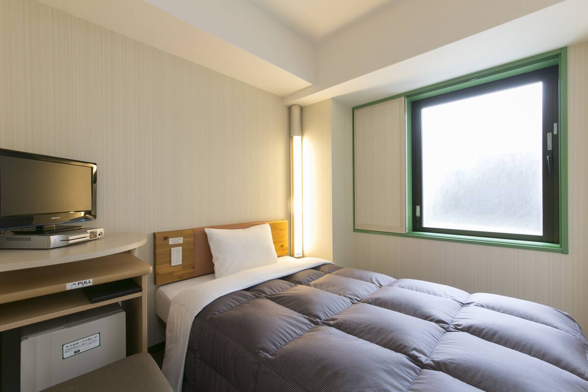 Une chambre d’hôtel comprenant un lit, un bureau escamotable avec un téléviseur, une fenêtre donnant sur un paysage agréable et une lampe de chevet.