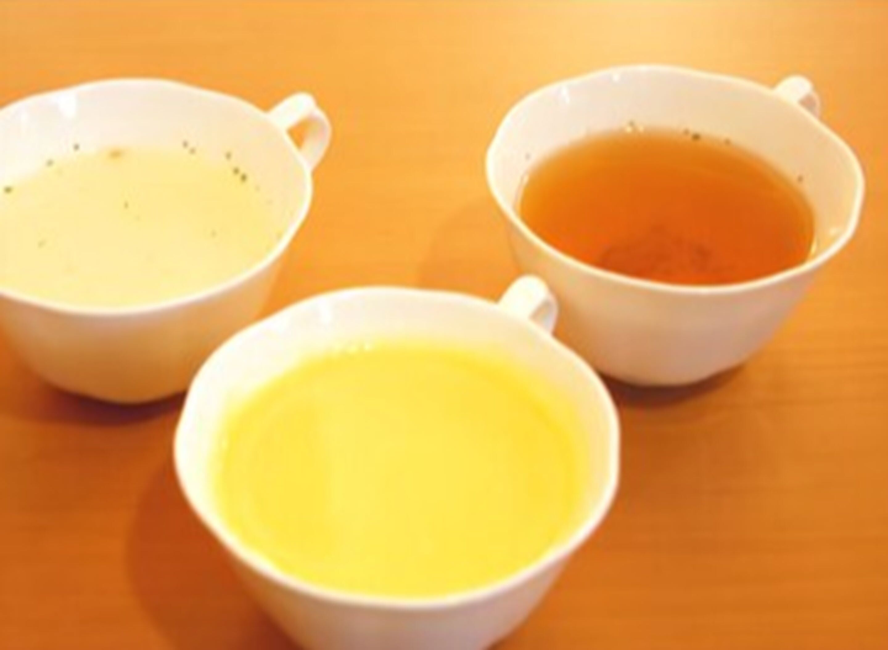 Three white cups on a wooden table.