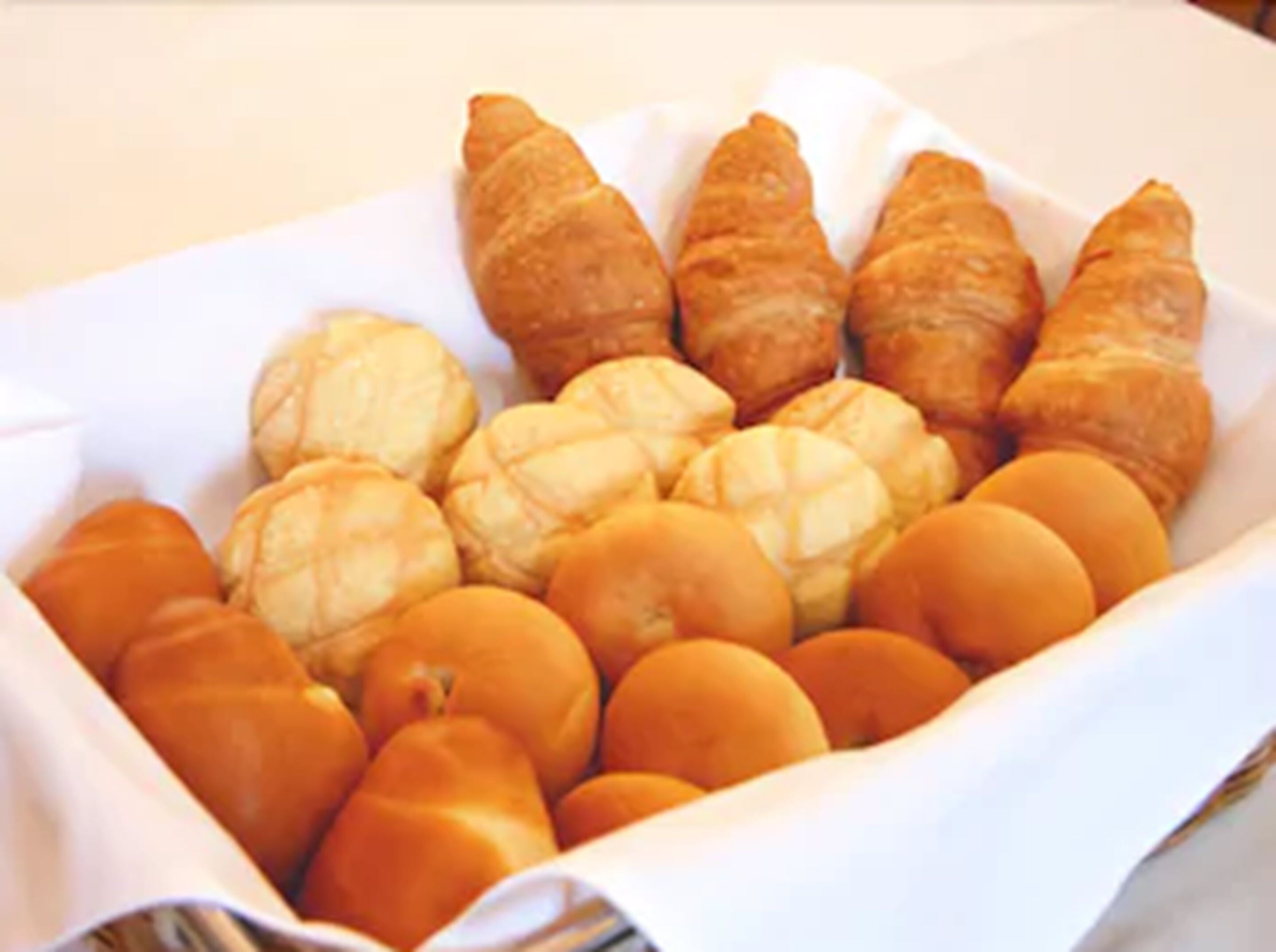 Una bandeja con una variedad de pasteles, incluyendo croissants y bollos redondos.
