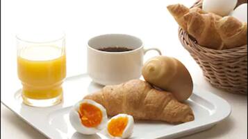 A breakfast tray with a croissant, a boiled egg, a glass of orange juice, and a cup of coffee.