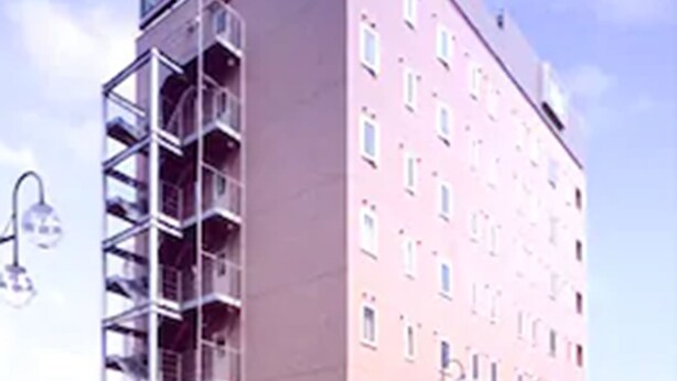 Un edifici de diversos pisos amb un atrium central i una zona d'entrada coberta.