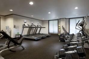 Un gimnasio con cintas de correr, mancuernas y un dispensador de agua.