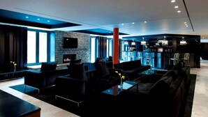 A modern lounge area with sofas, a fireplace, a bar, and a stone wall. - DoubleTree by Hilton Queenstown (Kawarau Falls)