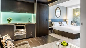 A modern hotel room with a kitchenette, a large bed, and a view of the city. - DoubleTree by Hilton Queenstown (Kawarau Falls)