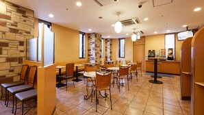 A restaurant with stone walls, multiple tables and chairs, and a counter with a coffee machine.