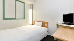 A hotel room with a single bed, a desk with a flat-screen TV, and a telephone.