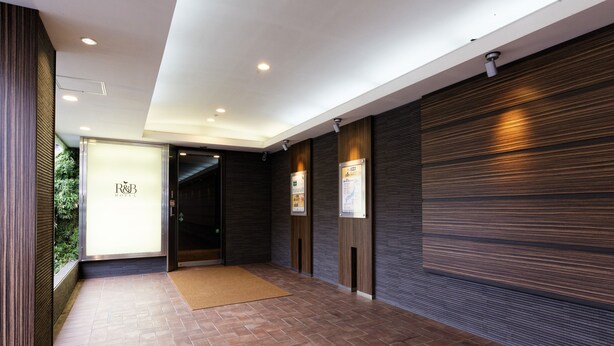 A hotel lobby with a tiled floor, a reception desk, and a door leading to the rooms.