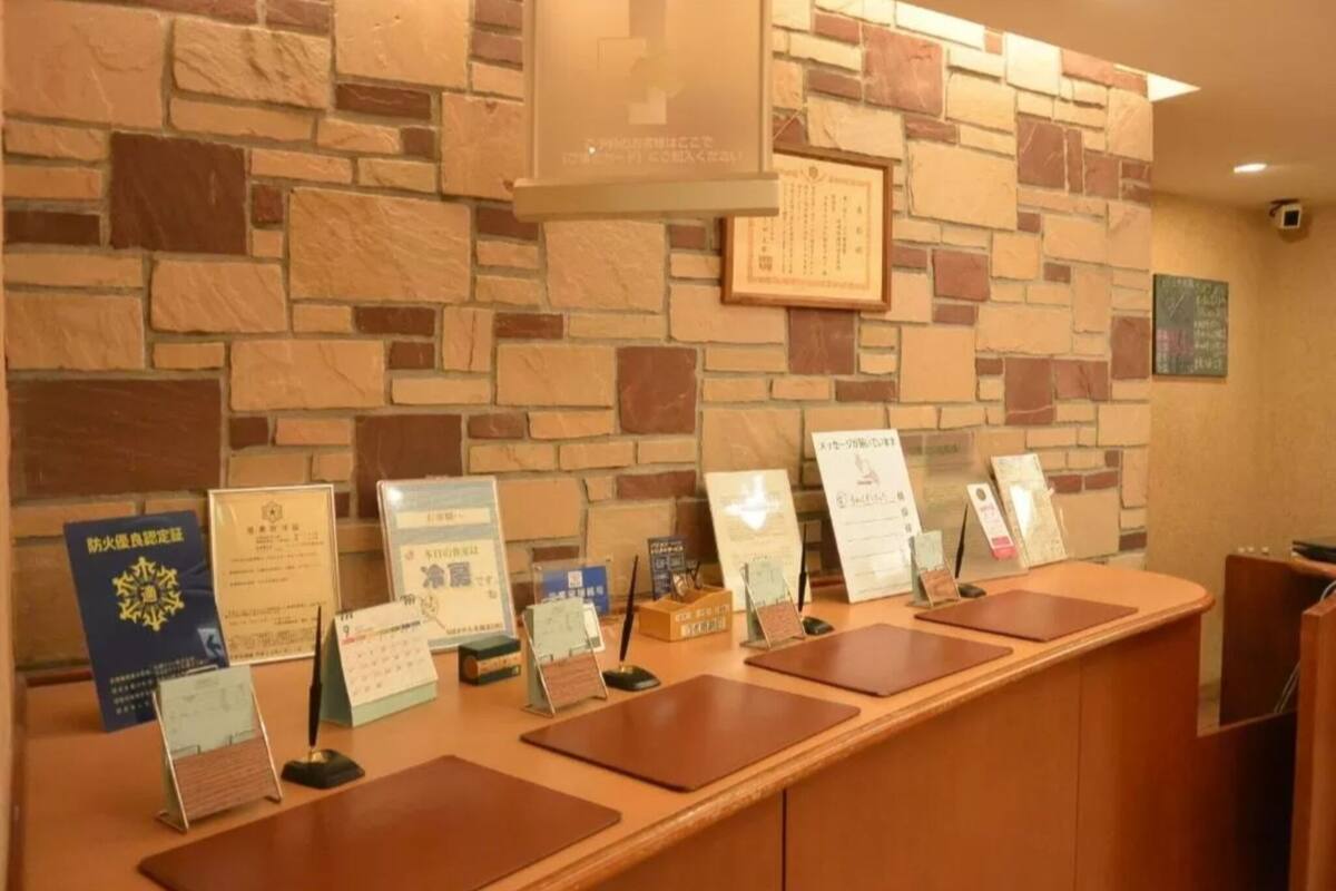 Un mostrador de recepción con certificados y placas en la pared de fondo.