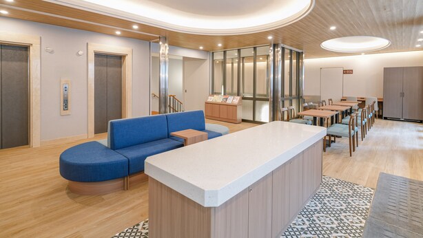 A modern interior with a reception desk, seating area, and a dining space.