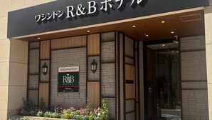 The exterior of Washington R&B Hotel with a stone facade, wooden accents, and a signboard.