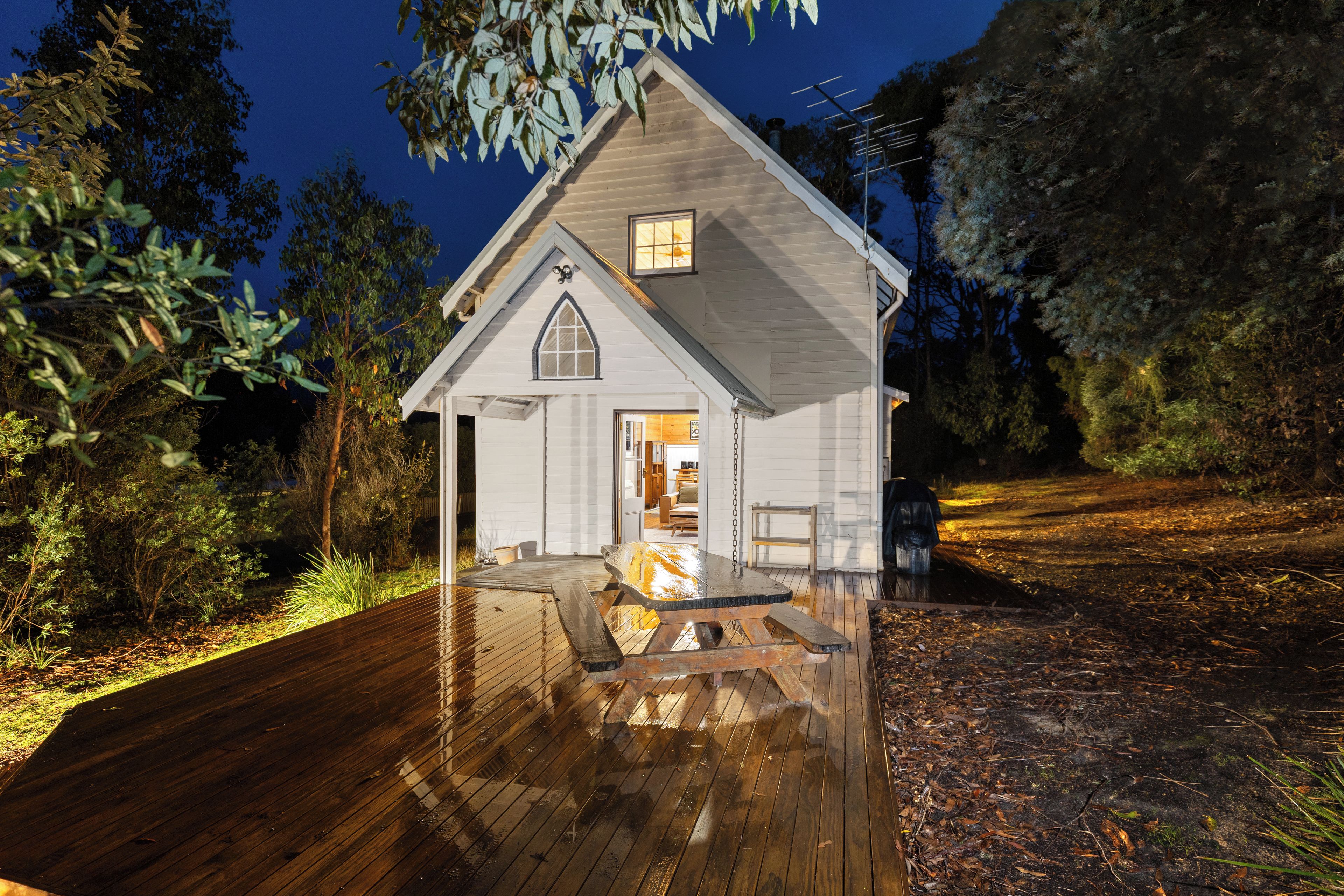 Une petite maison de plain-pied avec une terrasse en bois et un porche couvert.