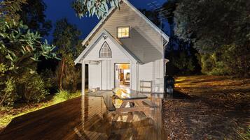 Une petite maison de plain-pied avec une terrasse en bois et un porche couvert.