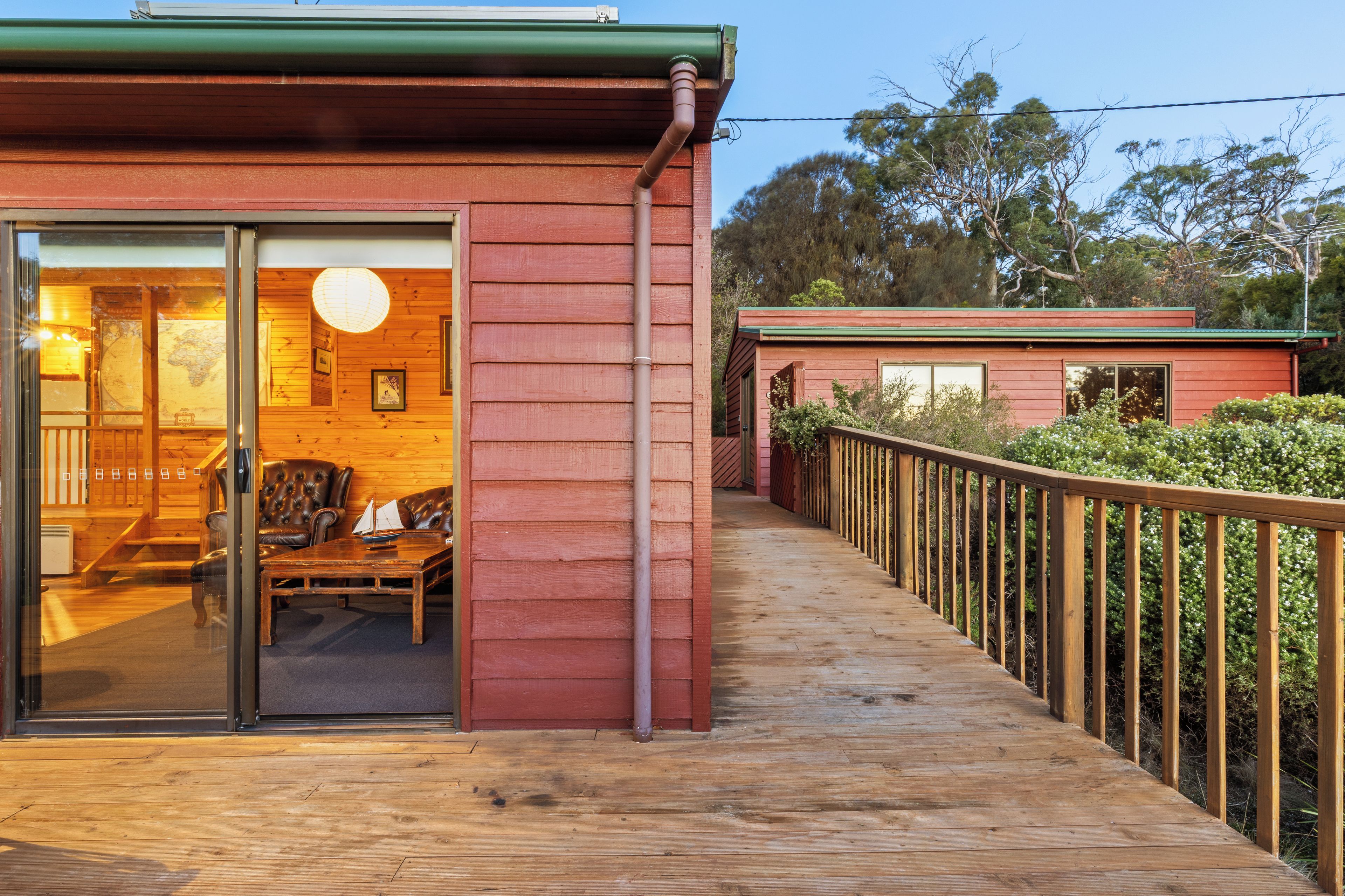 A wooden building with a glass door entrance, a deck, and a fenced area with trees.