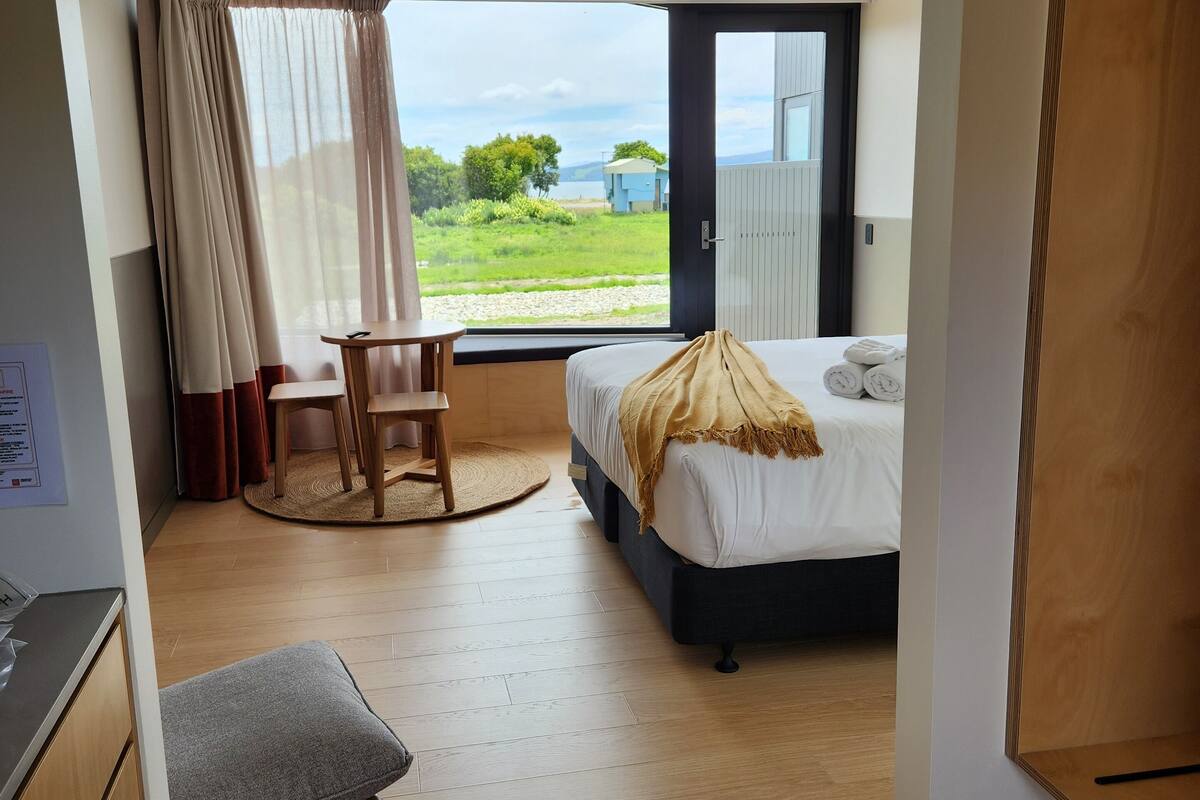 Une chambre à coucher avec un lit, un bureau et une vue sur l’extérieur.