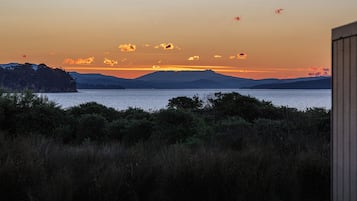 Eine Küstenlandschaft mit Blick auf das Meer und ferne Berge im Abendrot.