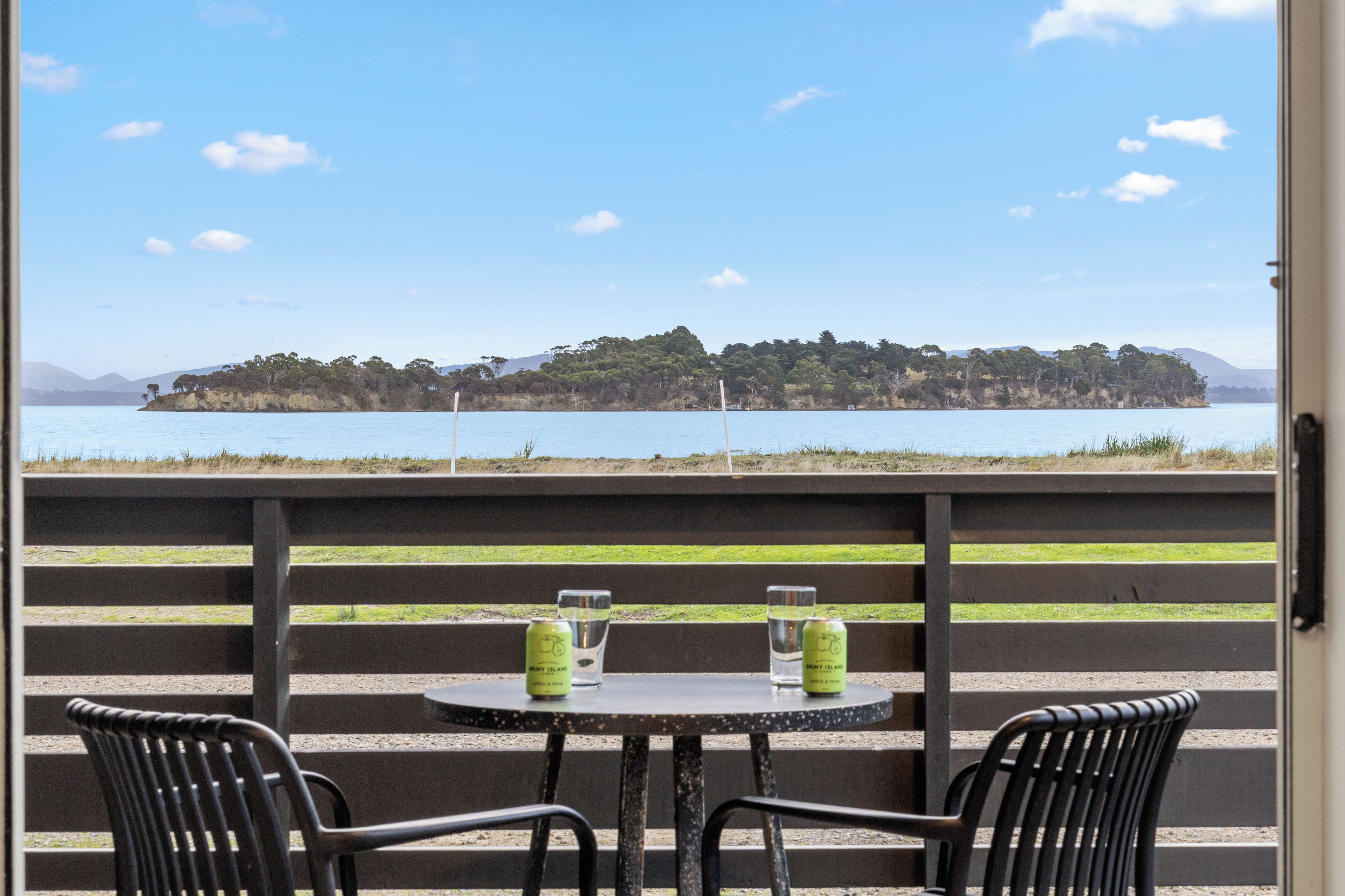 Una mesa con dos sillas y vista a un cuerpo de agua con una isla a lo lejos.
