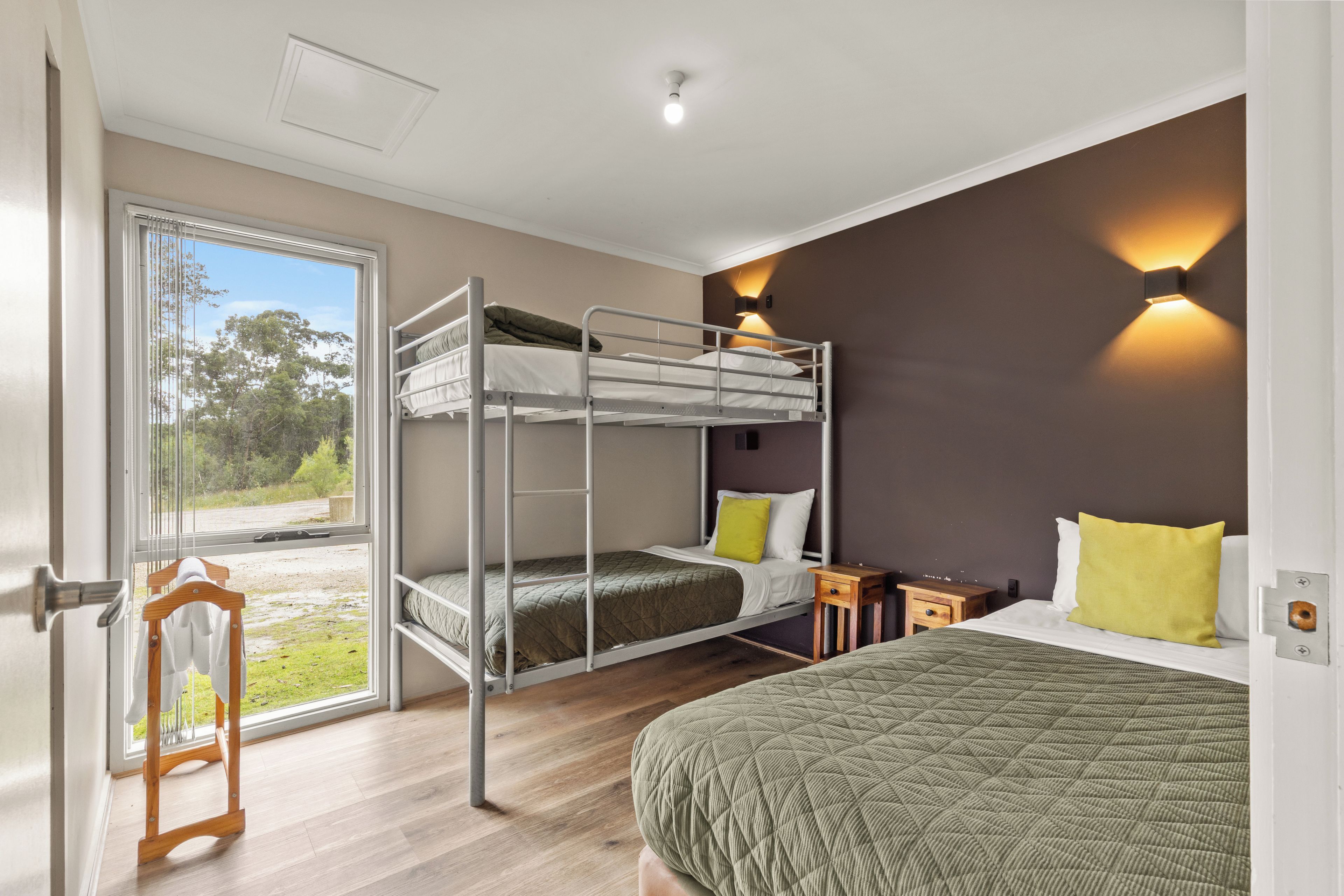 A room with a bunk bed, a single bed, and a wooden side table.