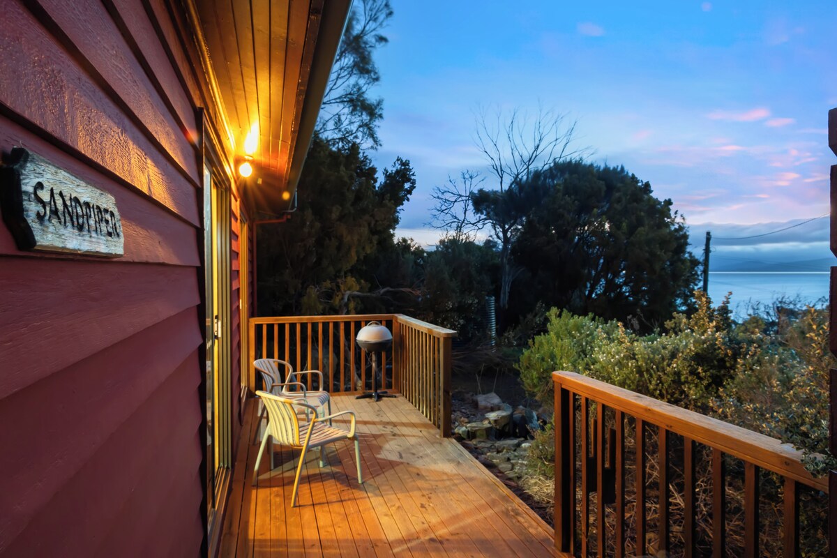 A wooden deck with a railing, a chair, and a sign that reads 'SANOMPIER'.