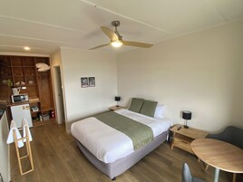 Un dormitorio con cama, escritorio, silla, armario y ventilador de techo.