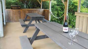 Un patio exterior con mesas de picnic y una botella de vino.