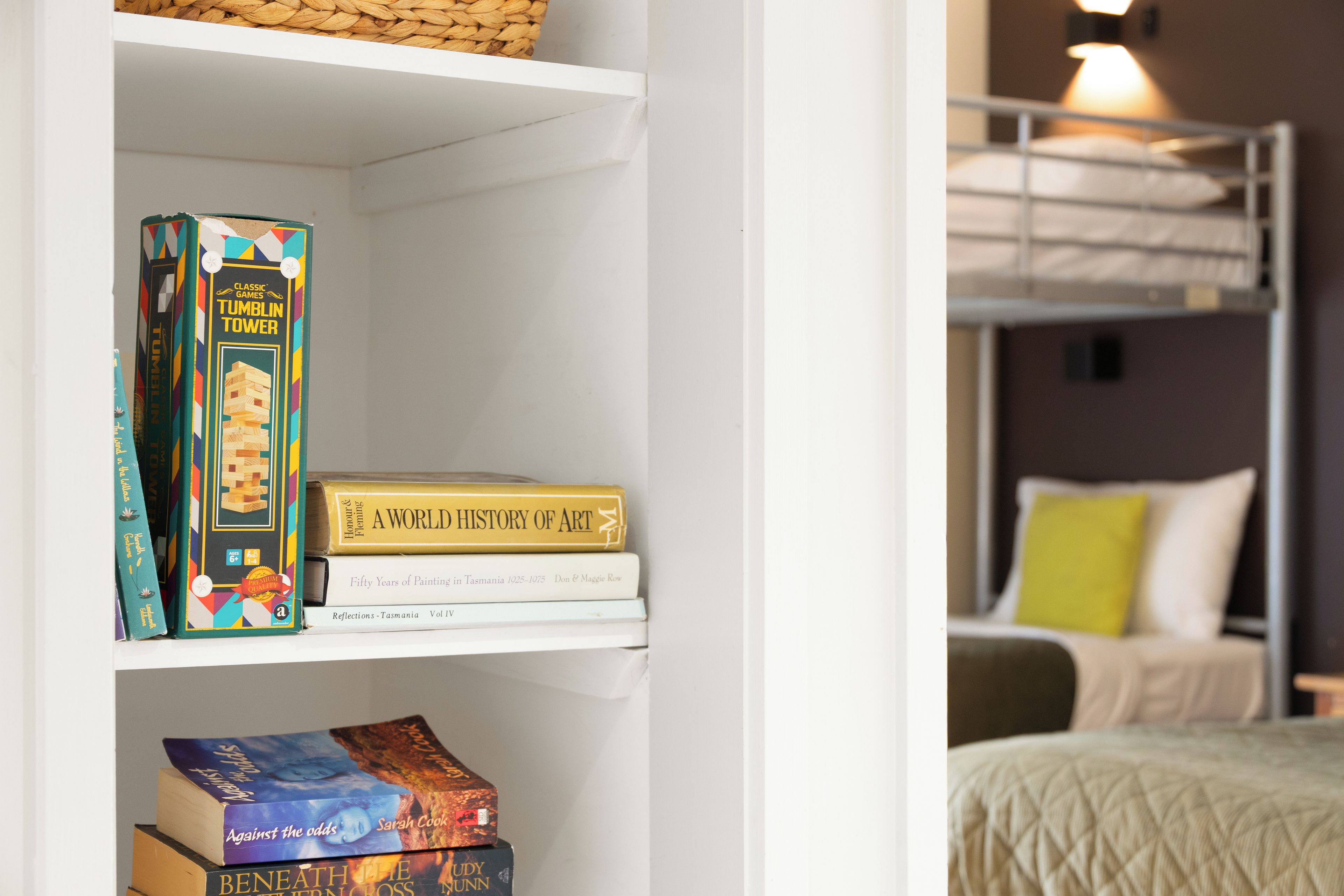 Una libreria con un gioco da tavolo, un libro intitolato 'A World History of Art' e un altro libro.