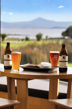 A table with two bottles of beer, a glass of beer, and a plate with cheese and crackers. - Bruny Island Escapes and Hotel Bruny (Alonnah)