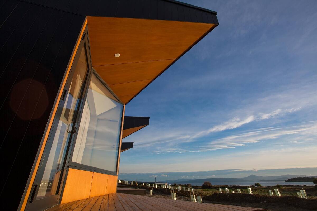 Un bâtiment moderne doté d’une grande façade en verre et d’un toit en pente recouvert de bois.