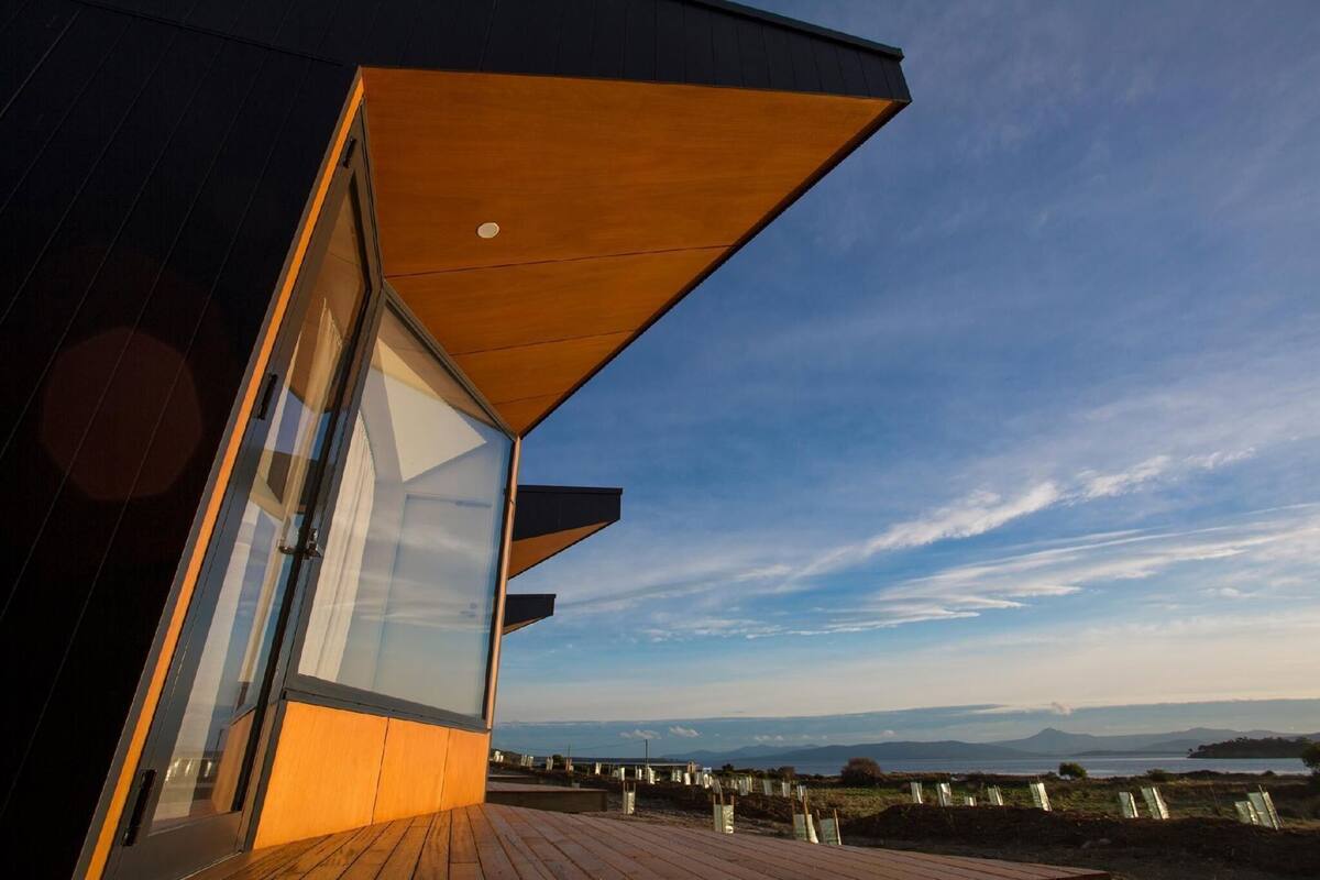 Un bâtiment moderne doté de grandes fenêtres en verre et d’une terrasse en bois.