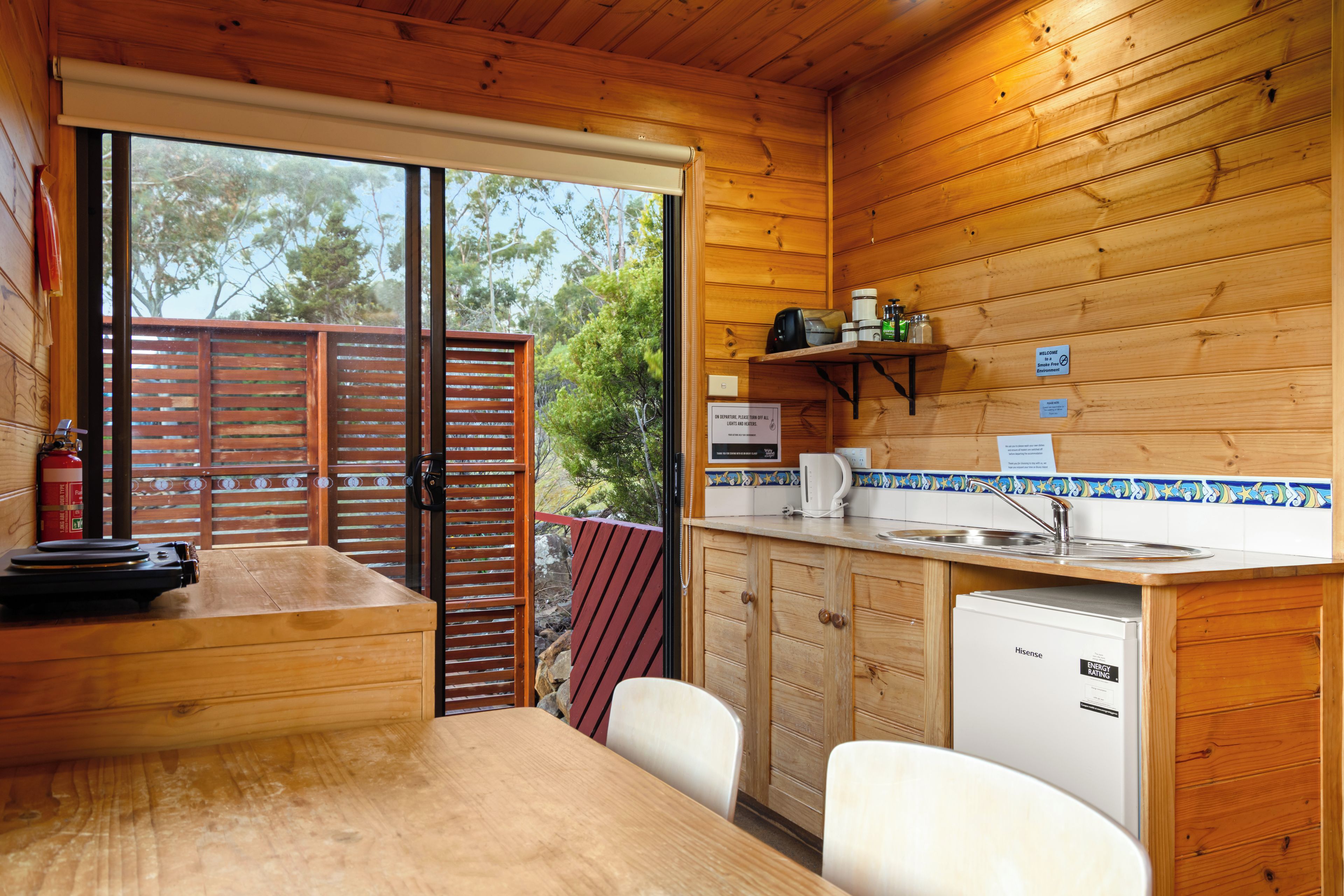 Een houten chalet met een keukenhoek, inclusief een gootsteen, een koffiezetapparaat en een koelkast.
